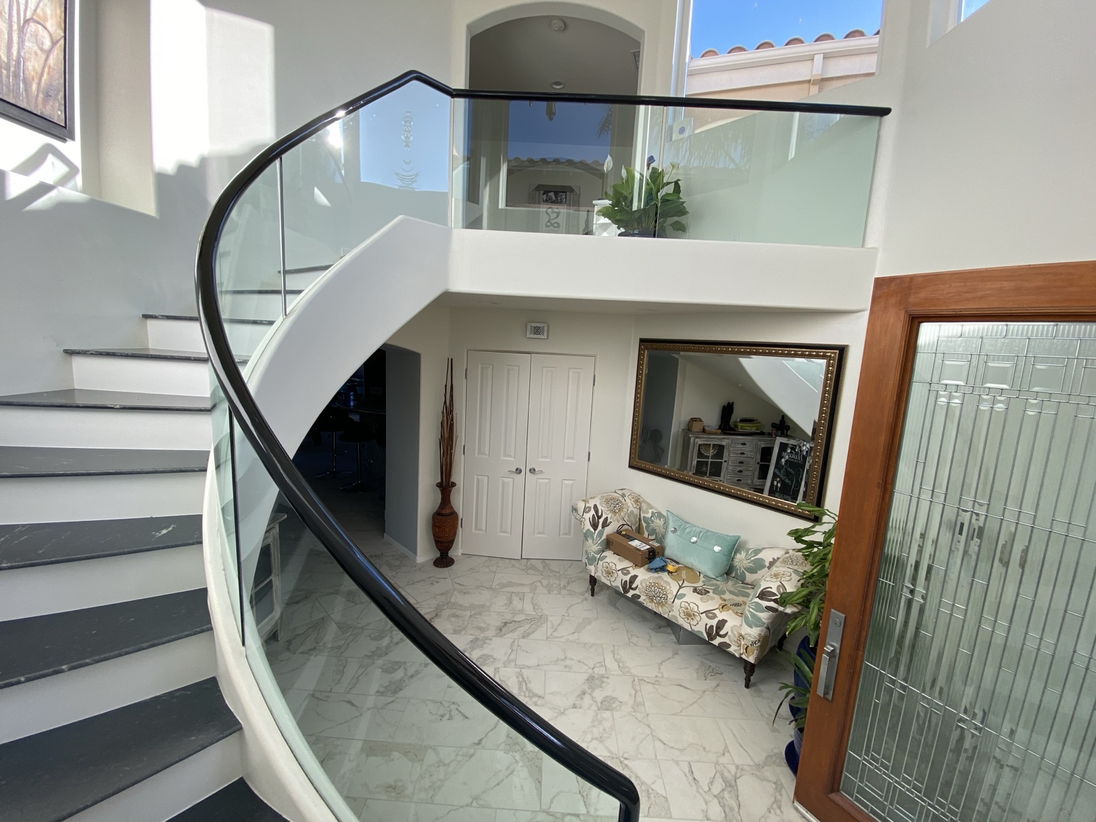 Curved black handrail following a staircase with glass panels
